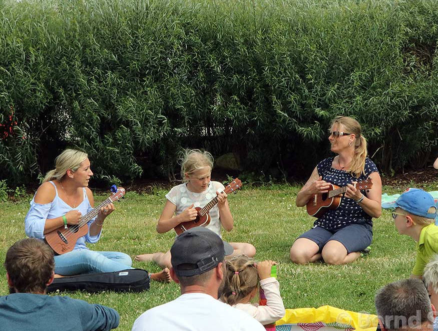 Musikschulkinder spielen Instrumente auf einer Grünfläche