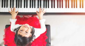 a girl is playing the piano and smiling