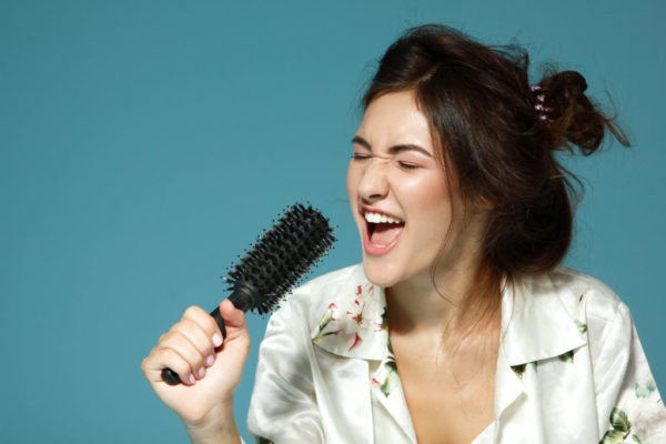 Cheerful attractive teen girl sing song holding comb like a micr Cheerful attractive teen girl sing song holding comb like a micr