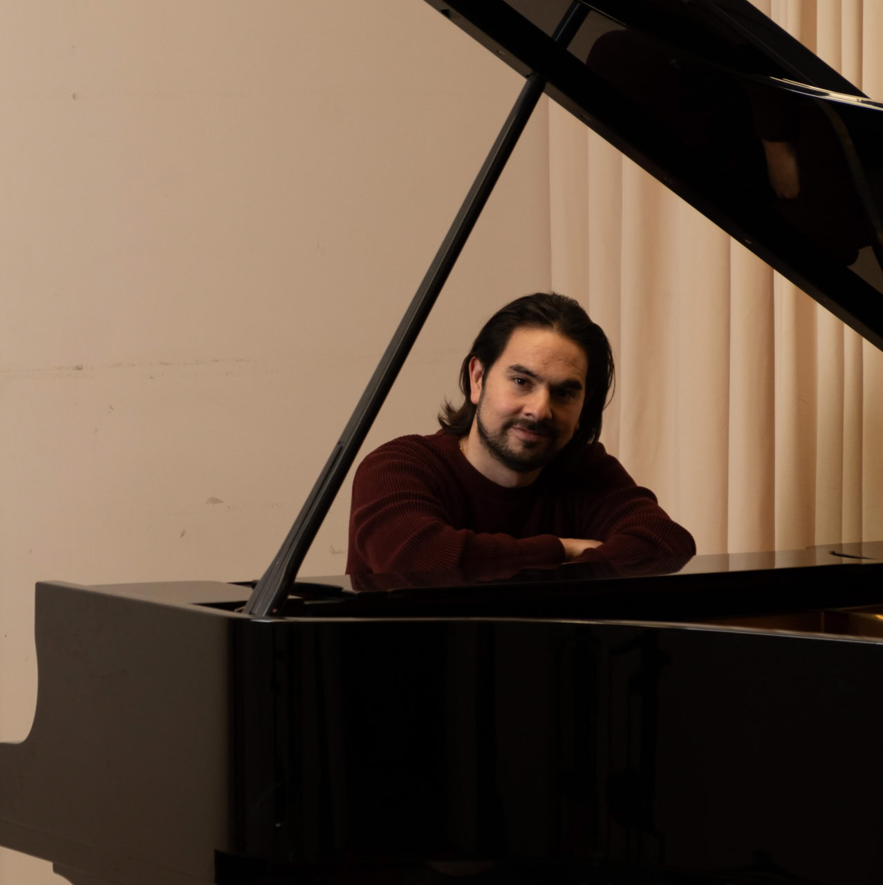 Ein Mann sitzt an einem Flügel und blickt freundlich in die Kamera